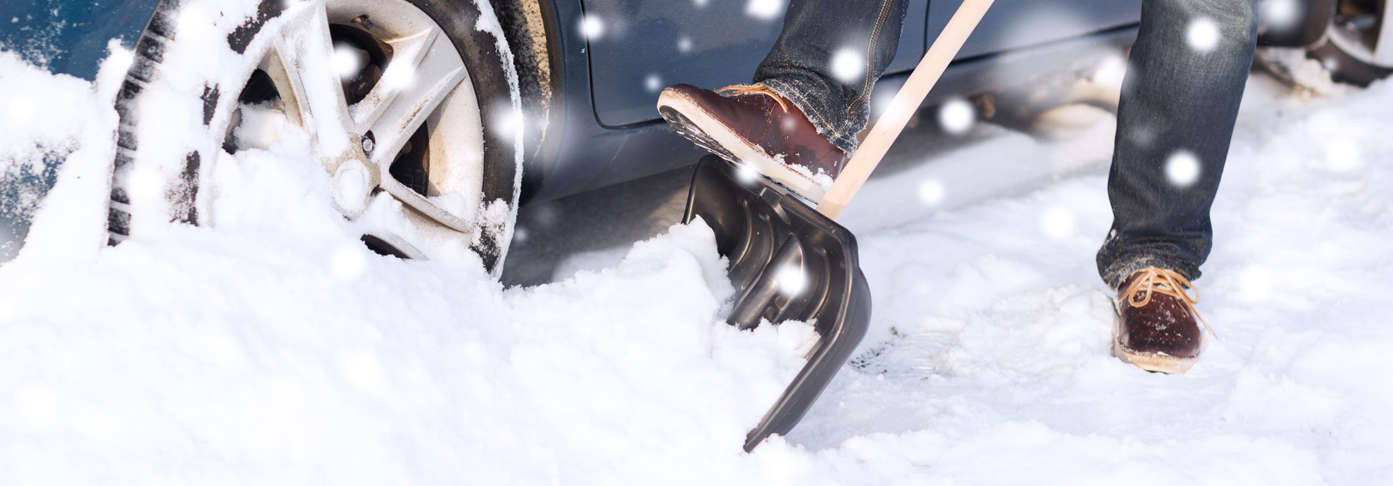 garage_parkering Person som skottar snö vid en bil